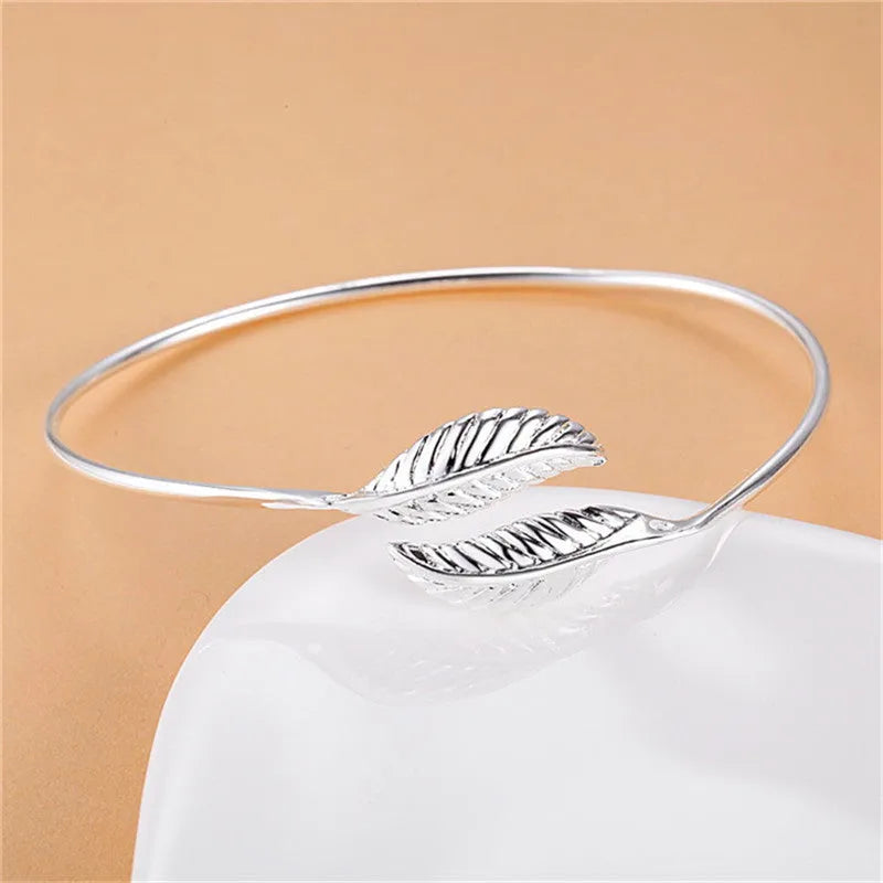 Silver metal bangle bracelet with open cuff design, 6.3cm diameter, on white background