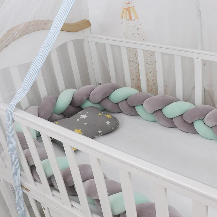 Braided knot crib bumper in spandex velvet, shown bending to fit a white wooden cot.