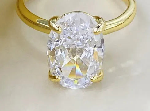 Women's oval four-claw solitaire ring with 6x9mm gemstone in gold or silver finish