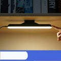 Modern LED desk lamp with touch controls and adjustable brightness settings on wooden desk