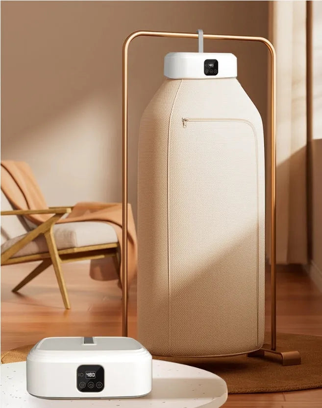 White cylindrical compact foldable laundry dryer with remote control on a table.