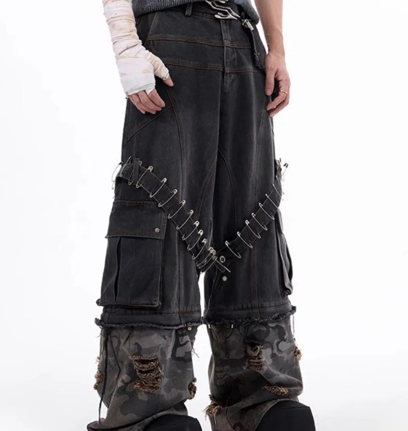 Grey men's jeans with camouflage pattern and spliced construction, showing pin and ribbon details.