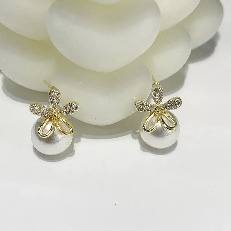 Pair of pearl flower drop earrings in gold and silver finishes on a light background