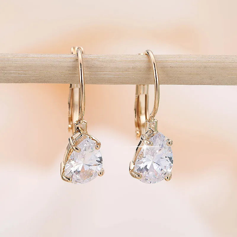 A pair of women's drop-shaped fashion earrings in gold or platinum finish with a platinum-inlaid gemstone.