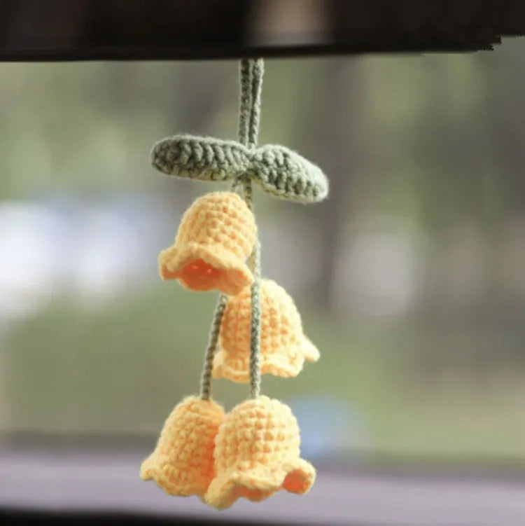 Green and white knitted wool car plant decoration with macramé texture and a white hanging rope.