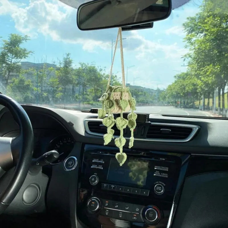 Green and white knitted wool car plant decoration with macramé texture and a white hanging rope.