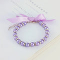 Small dog wearing adjustable pearl and rhinestone necklace with ribbon bow in pink colour
