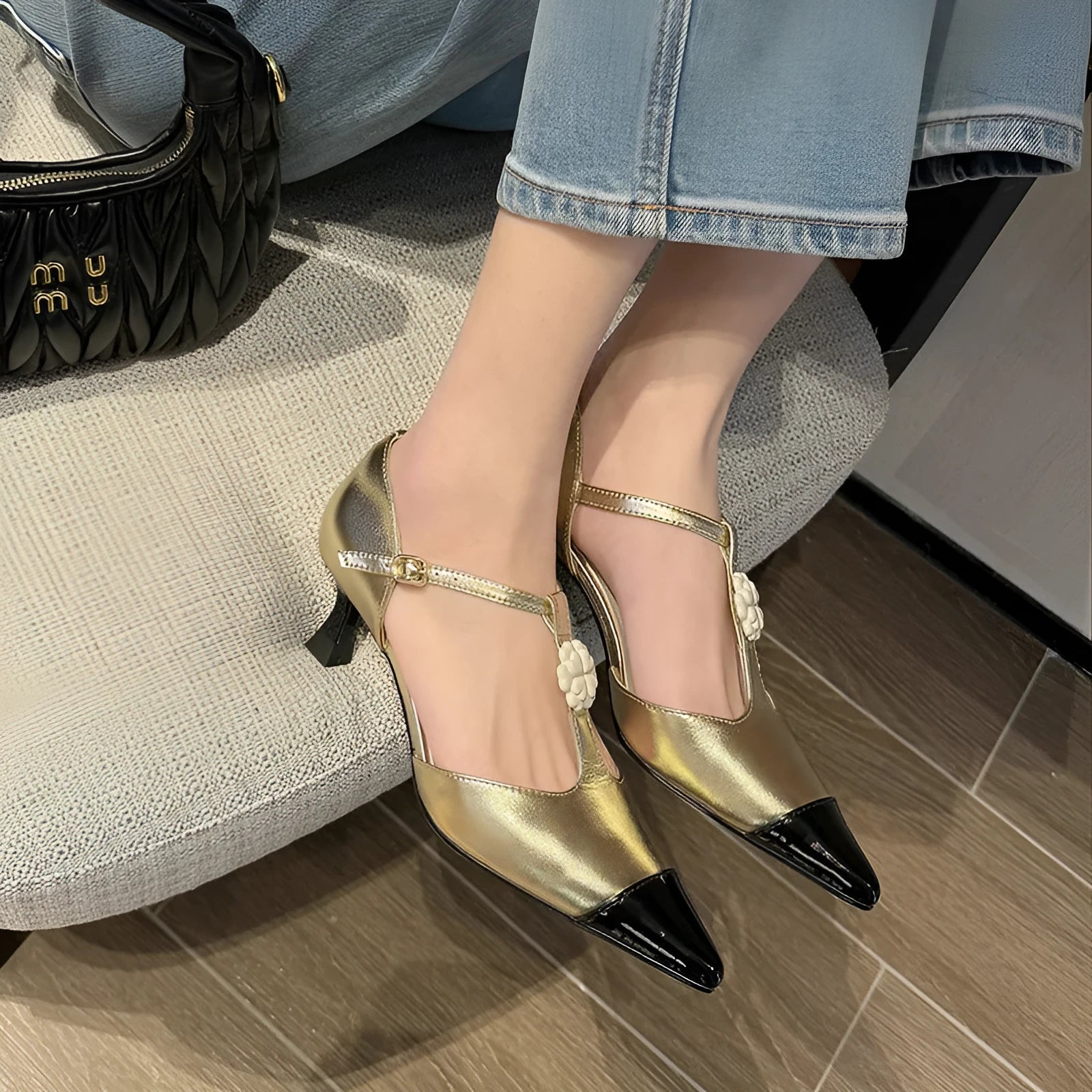 Women's gold stiletto heel shoe with pointed toe, flower buckle, and shallow mouth design on a beef tendon sole.