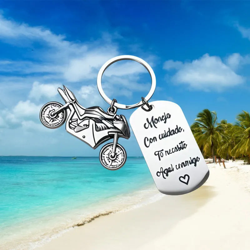 Stainless steel key ring with etched motorcycle design next to a grey flannel drawstring bag.