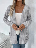 Plus size woman wearing a long sleeve grey cardigan with front pockets, loose fit.