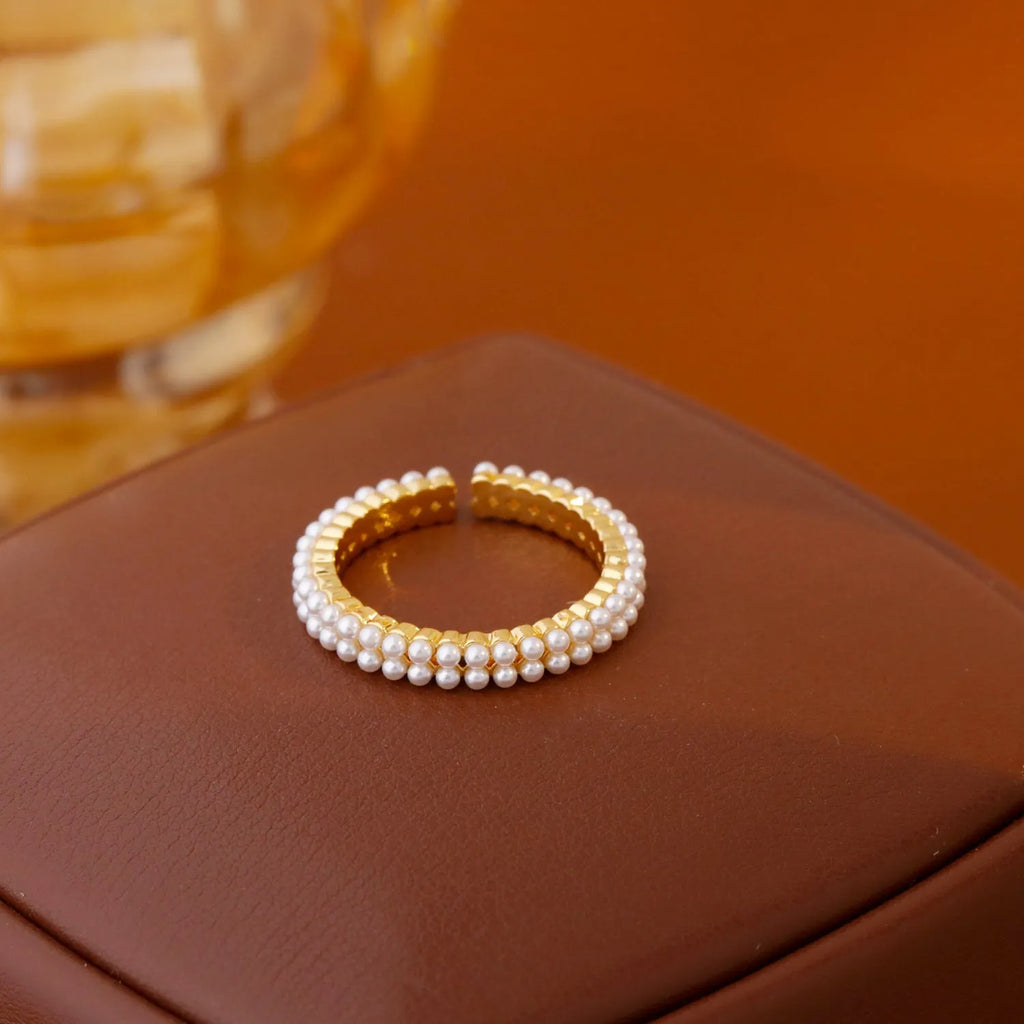 Gold electroplated open mouth geometry pearl ring for women on a neutral background.