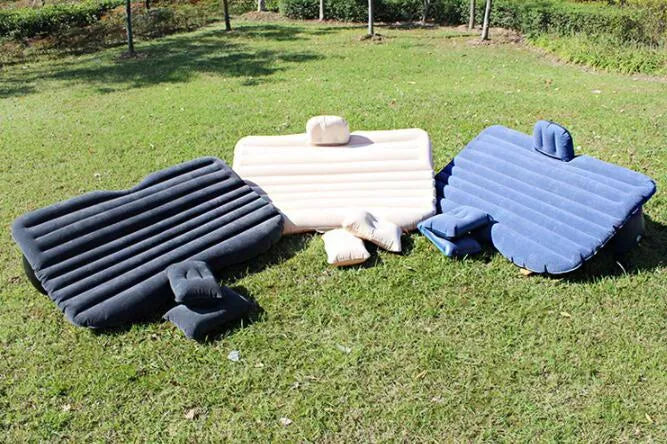Black inflatable car bed with flocked surface set up in the back of a five-seater vehicle with pillows.