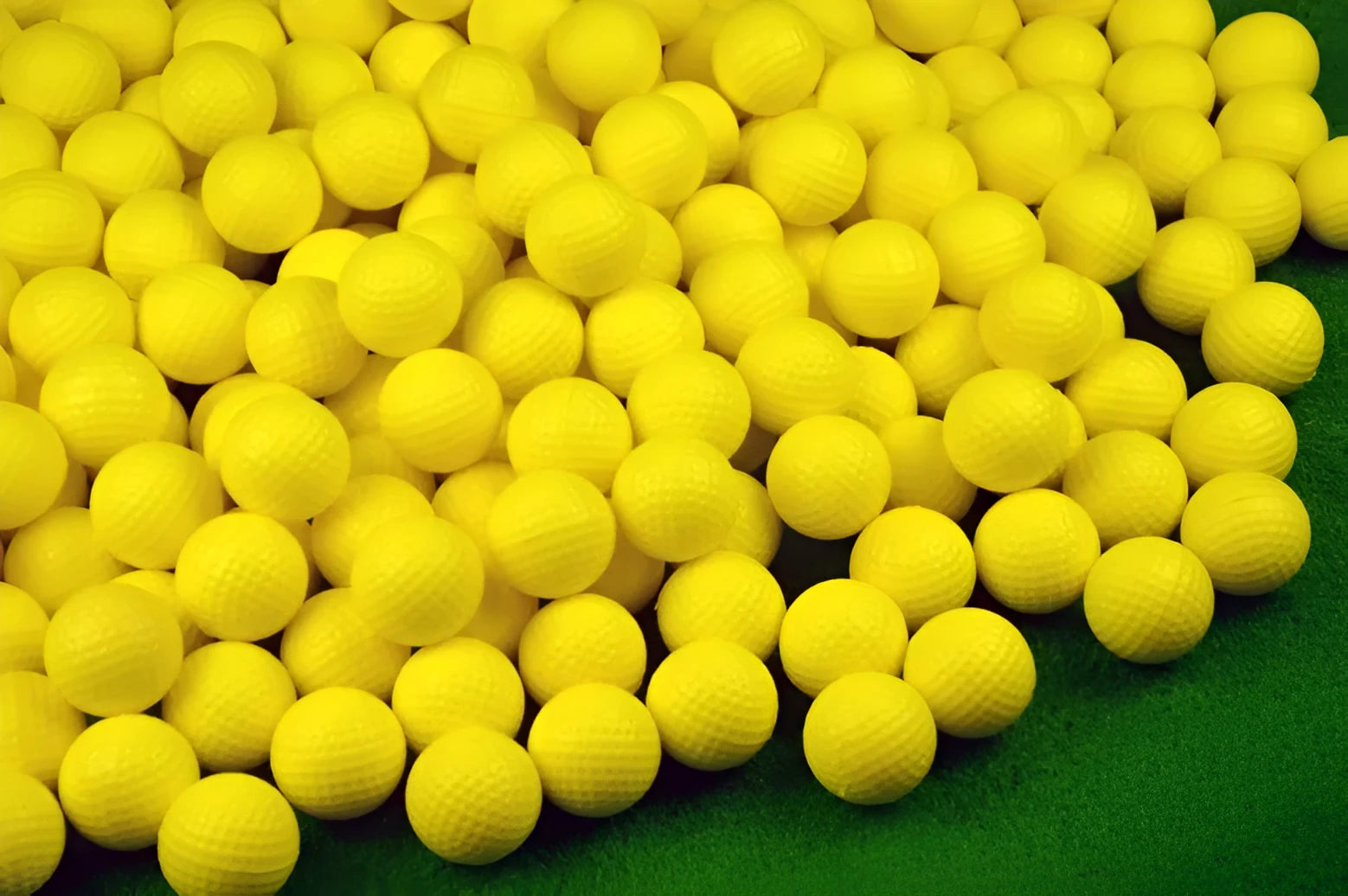 10 yellow PU foam indoor practice golf balls with 41mm diameter on a green surface