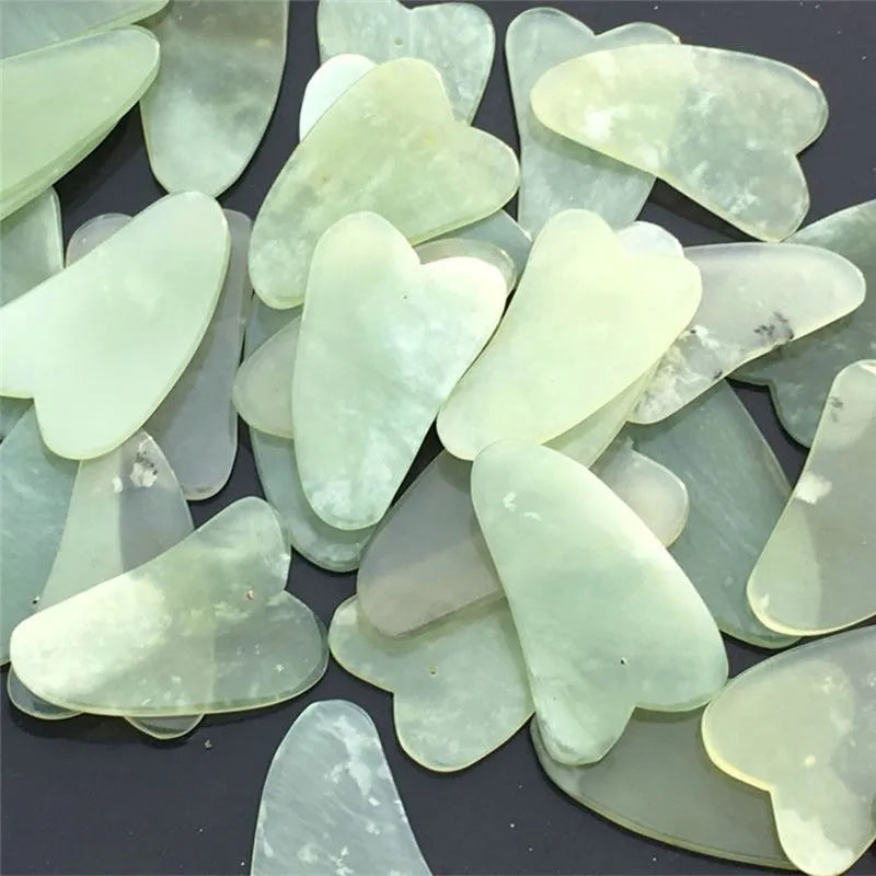 Natural jade gua sha scraper in heart shape on a light surface, 6.3cm x 4.5cm, hand-polished stone