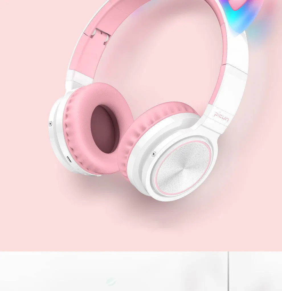 Pink and white Luminous Bluetooth wireless over-ear headset with microphone on a table.