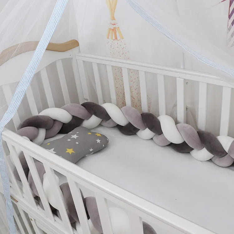 Braided knot crib bumper in spandex velvet, shown bending to fit a white wooden cot.