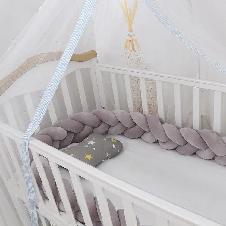 Braided knot crib bumper in spandex velvet, shown bending to fit a white wooden cot.