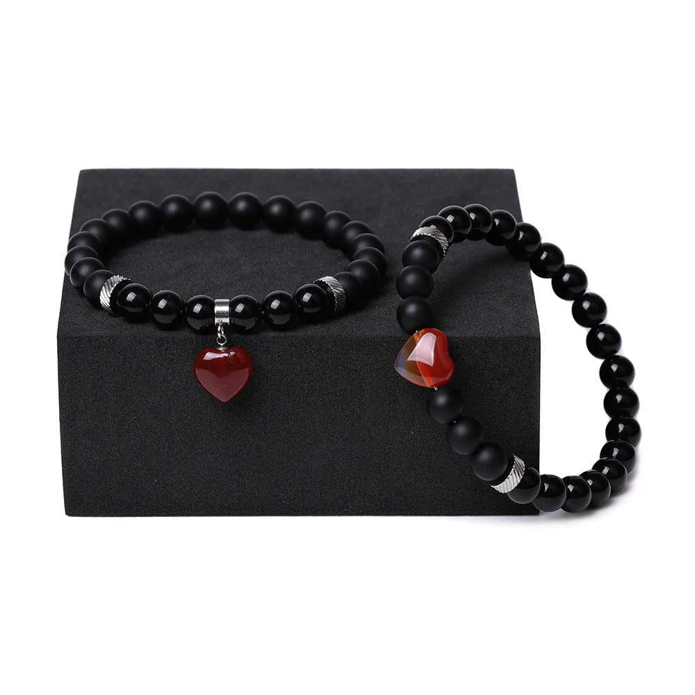 A pair of matching bracelets with polished geometric heart pendants made from natural stone.