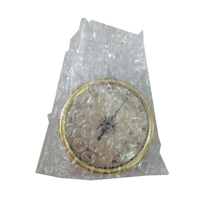 Analogue thermometer and hygrometer with aluminium dial on a white wall.