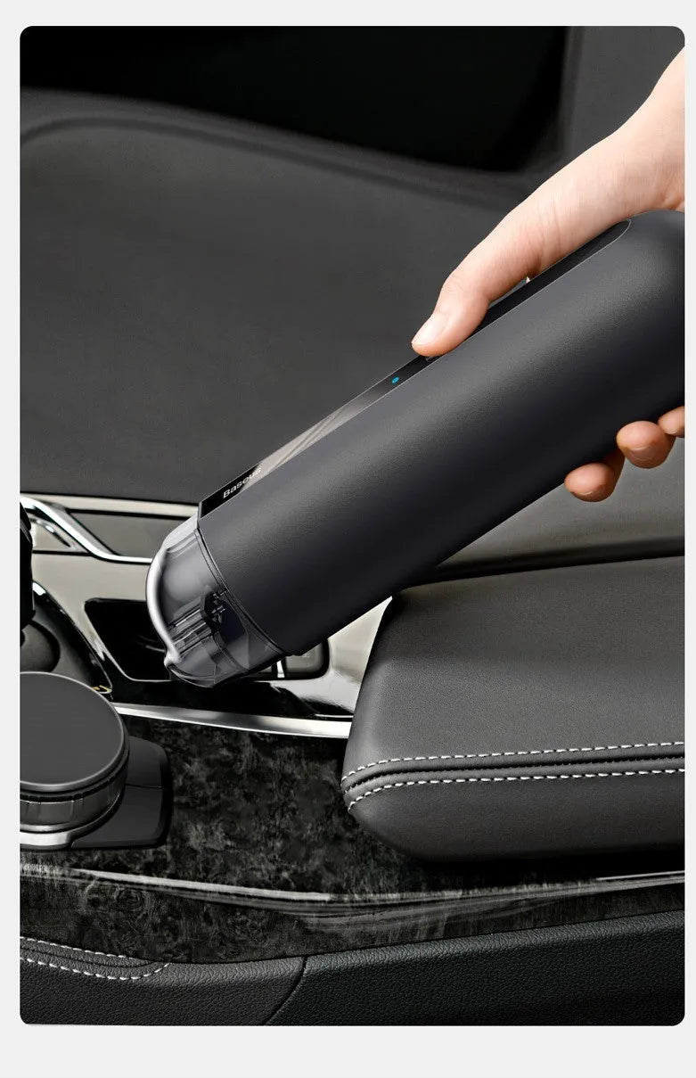 Black cordless handheld car vacuum cleaner with blowing hose attachment on a desktop.