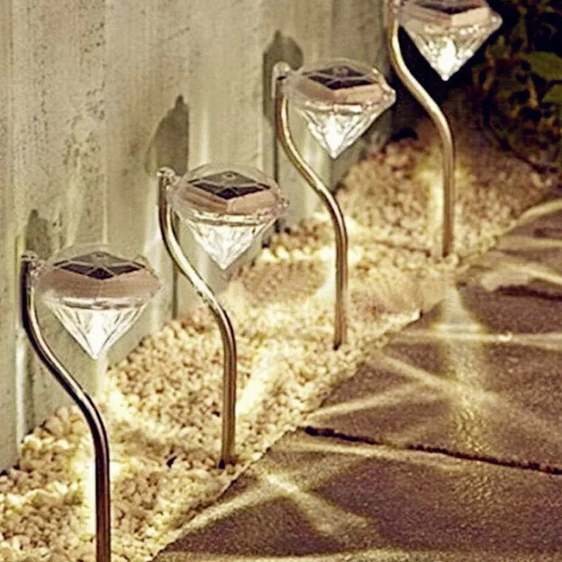 White solar-powered diamond-shaped garden spotlight with adjustable head on a stake.