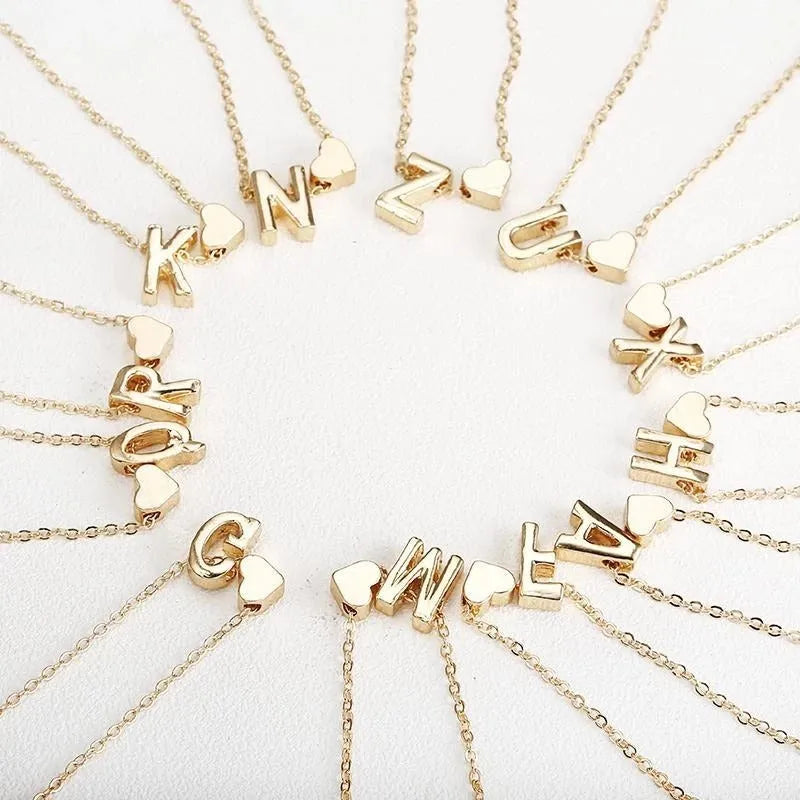 Golden peach heart shaped alloy necklace pendant with a letter design on a white background.