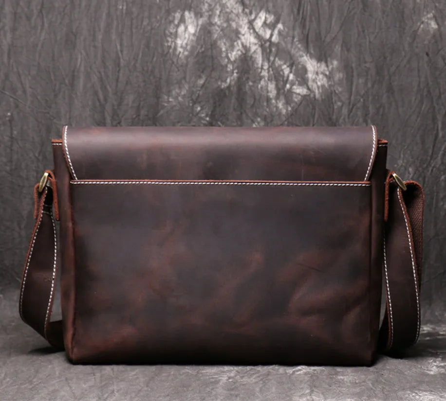 Men's vintage brown leather messenger bag with adjustable strap, shown open to reveal internal organiser pockets.