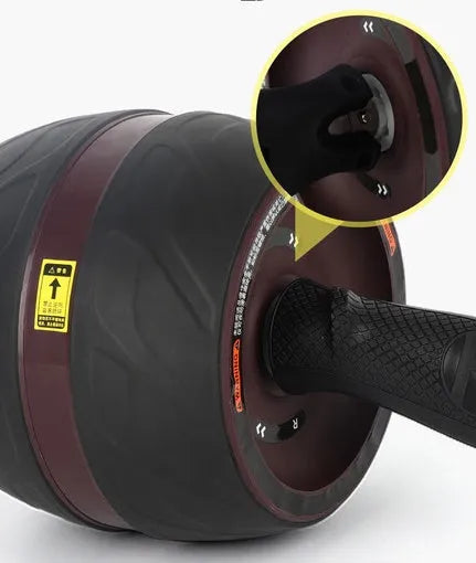 Home abdominal wheel in Black red with PP handle and spring boost mechanism on a flat surface