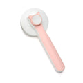 Blue self-cleaning slicker brush for dogs and cats on a table, showing ergonomic rubber handle and stainless steel pins.