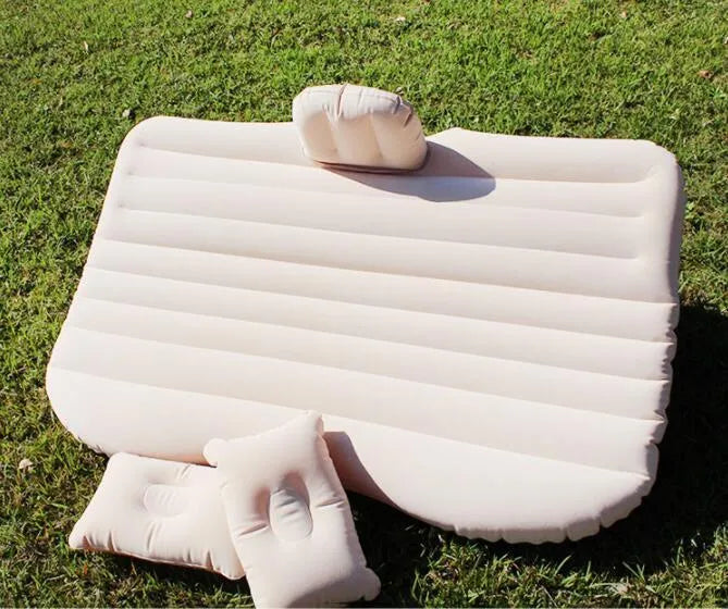 Black inflatable car bed with flocked surface set up in the back of a five-seater vehicle with pillows.