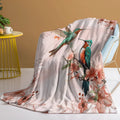 Hummingbird floral fleece throw blanket in pink flannel velvet, shown on sofa with hemmed edges