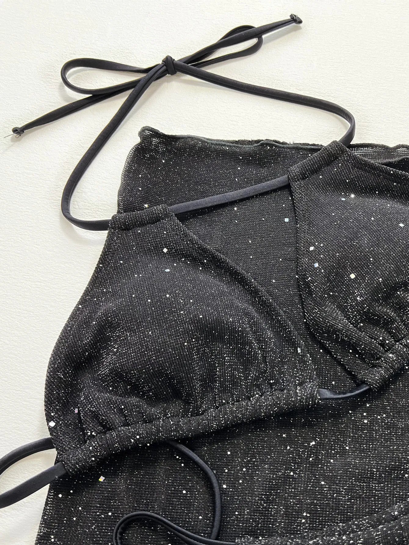 Black three-piece polyester bikini swimsuit set showing top and shorts.