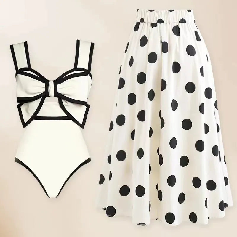 A black one-piece swimsuit for women with a white detachable skirt and a decorative bow at the front.