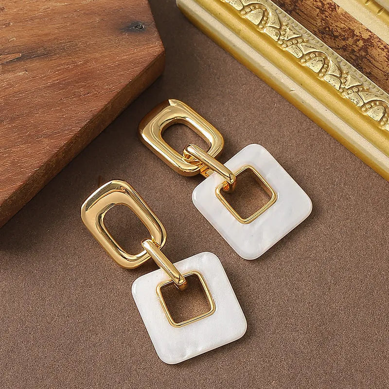 A pair of hollow geometric square earrings with chamfered corners in an electroplated copper finish.