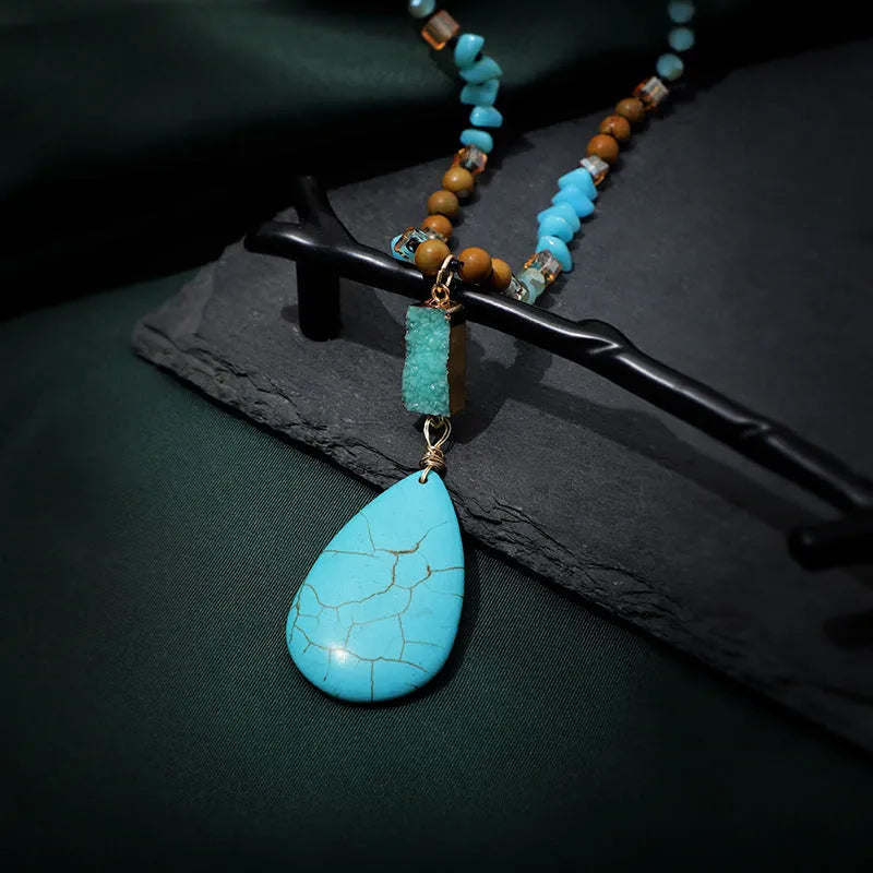 Close-up of a large turquoise blue heart-shaped water drop pendant necklace on a ball bead chain.