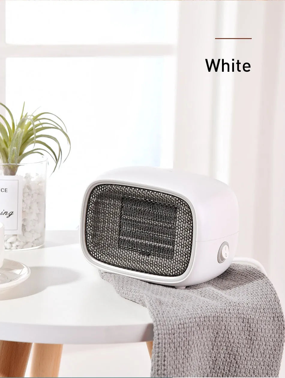 Compact green mini ceramic heater with metal mesh front on a wooden desk