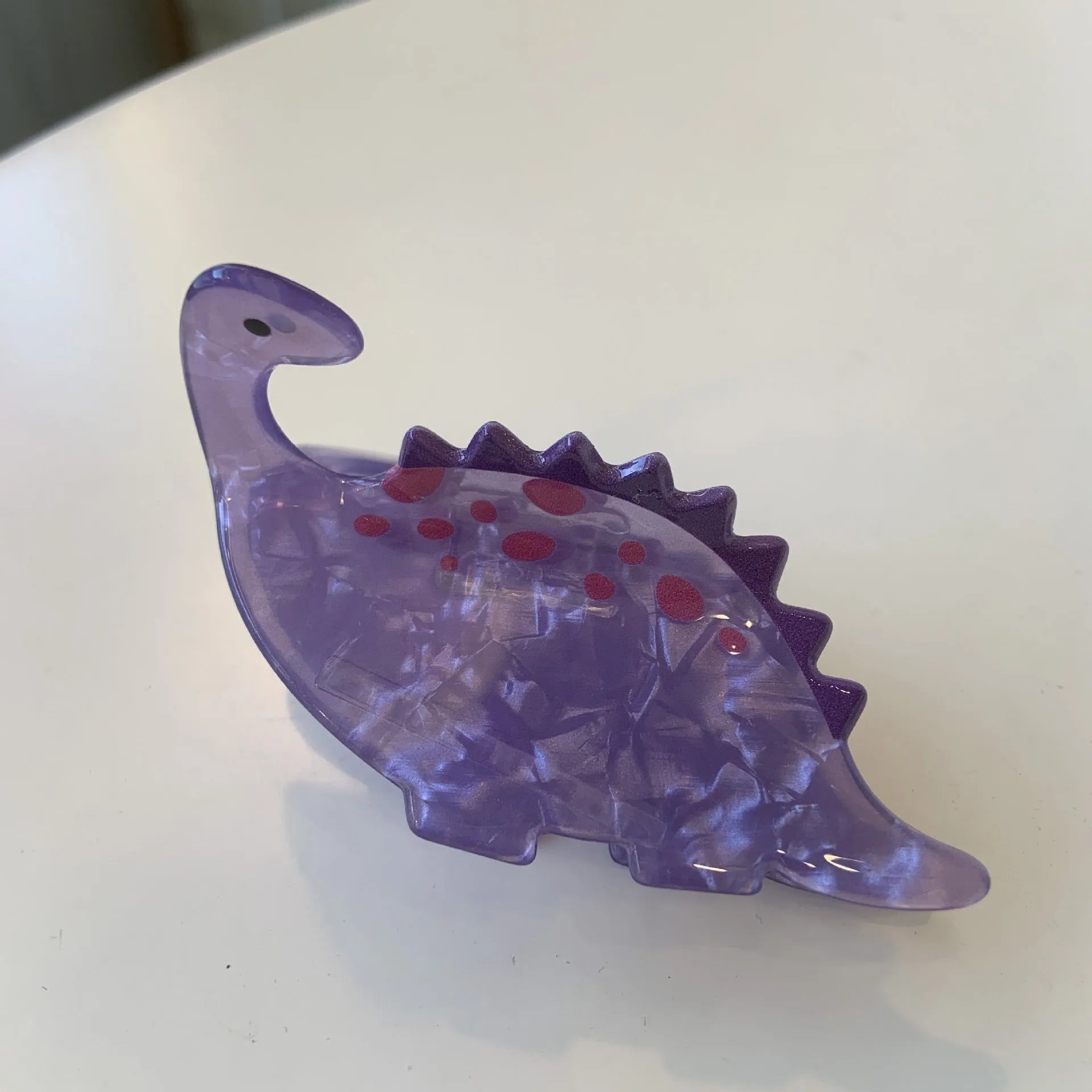 Acrylic hair clip with dinosaur design in various colours including blue, brown, green, pink and purple variants