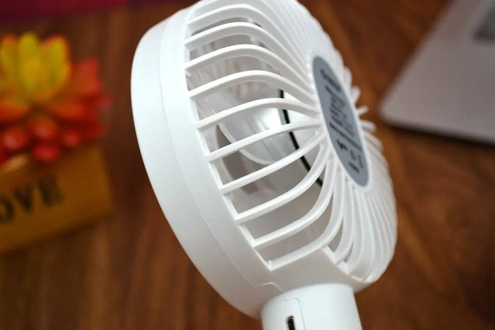 White ORICO FH1 handheld USB rechargeable desk fan with three-speed control on a desk.