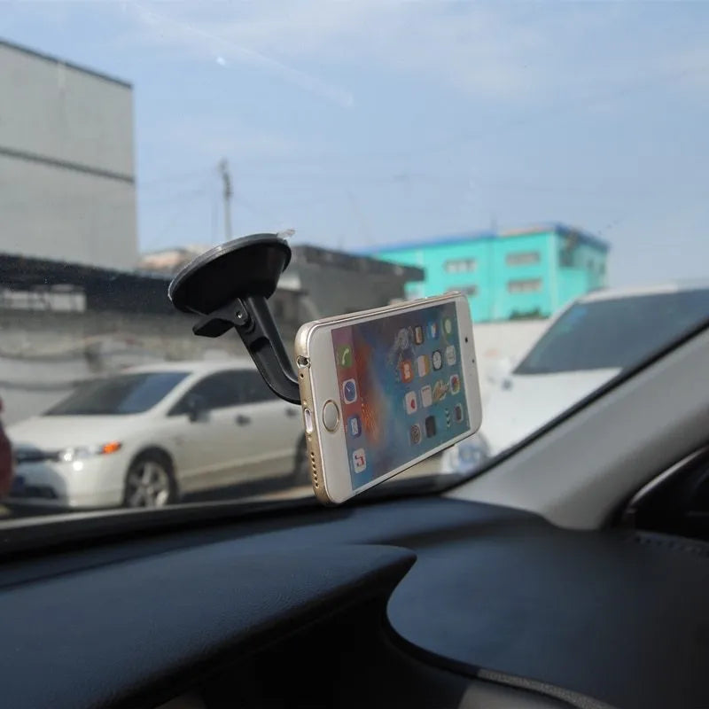 Classic black magnetic car phone holder on dashboard with phone attached, 360-degree rotatable design