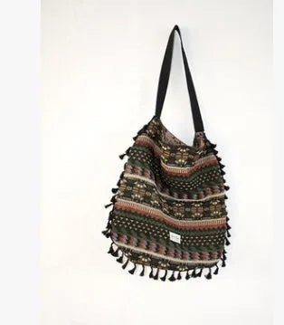 Green geometric tribal tasselled tote bag with oval shape, open top, and two handles, shown on a flat surface