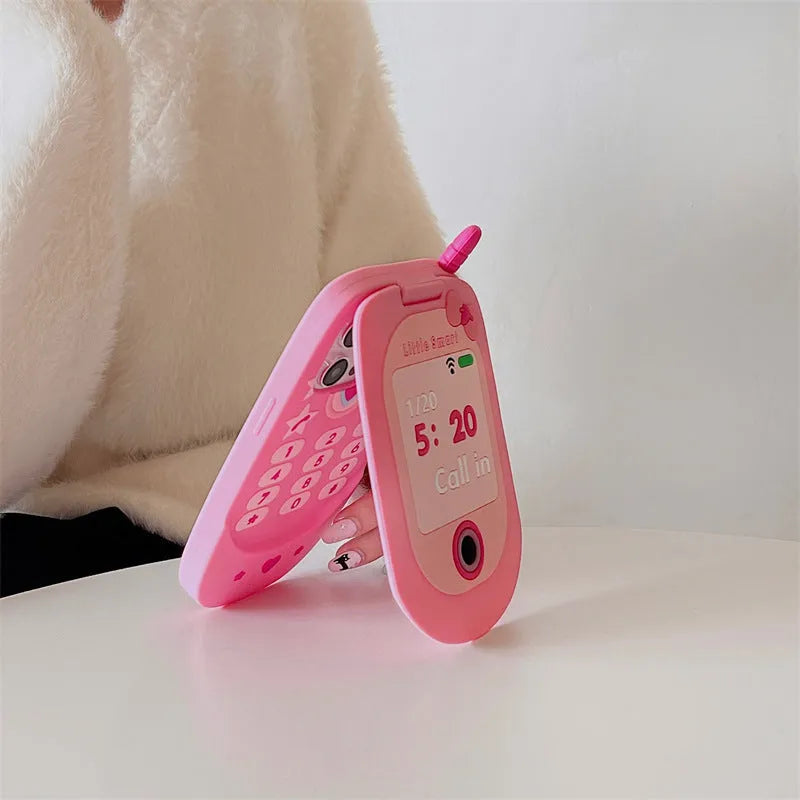 Pink silicone iPhone case shaped like a flip phone with a built-in mirror, showing cute cartoon style.
