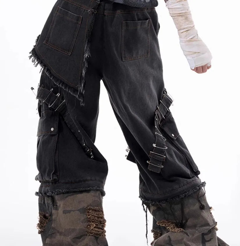 Grey men's jeans with camouflage pattern and spliced construction, showing pin and ribbon details.