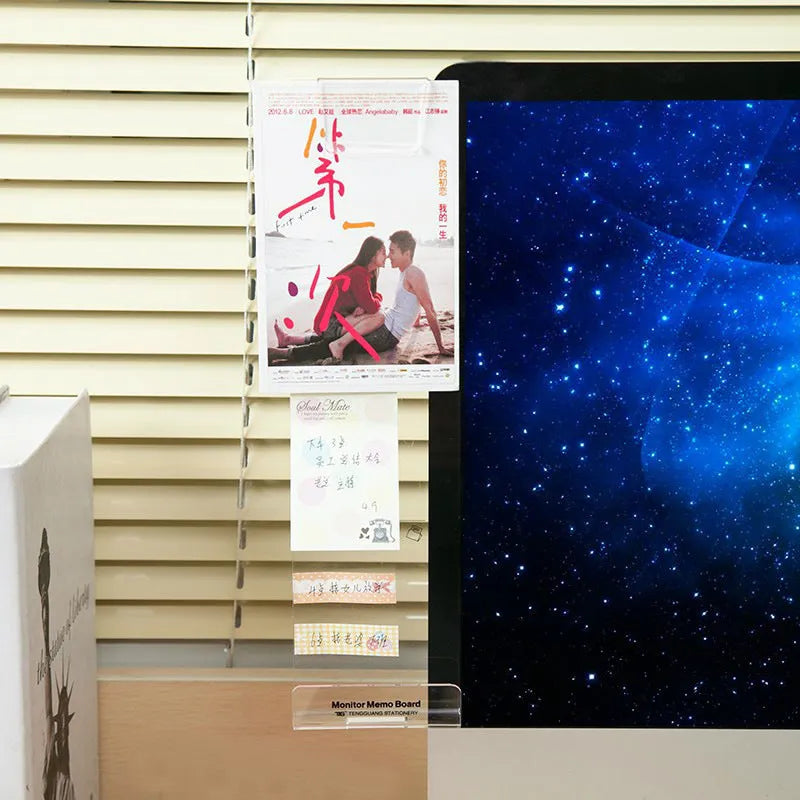 Acrylic monitor message memo board attached to monitor with wall suction, holding a post-it note