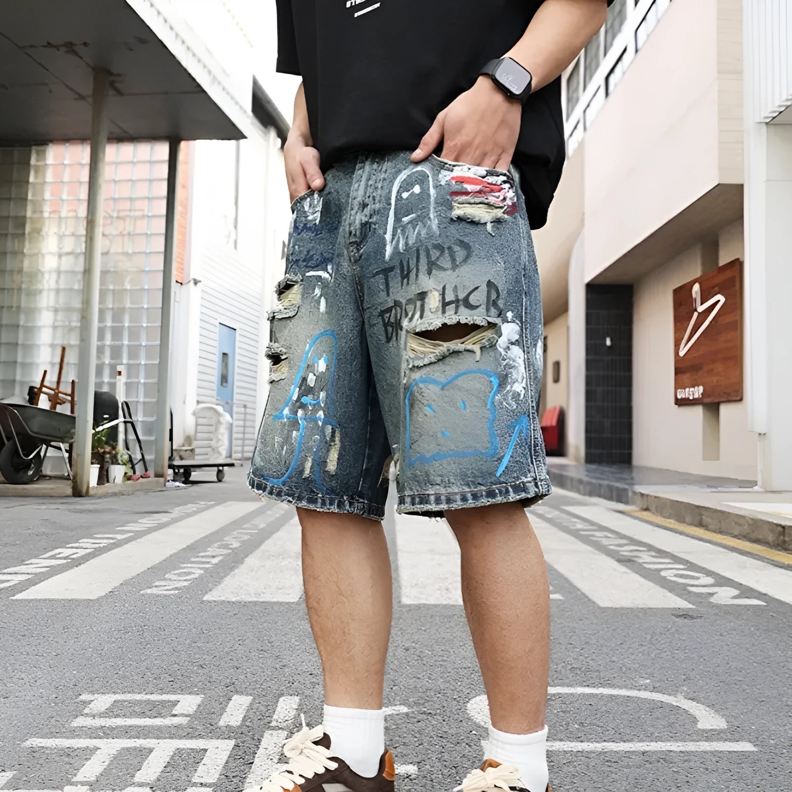 Men's blue ripped denim shorts with graffiti design and straight leg.