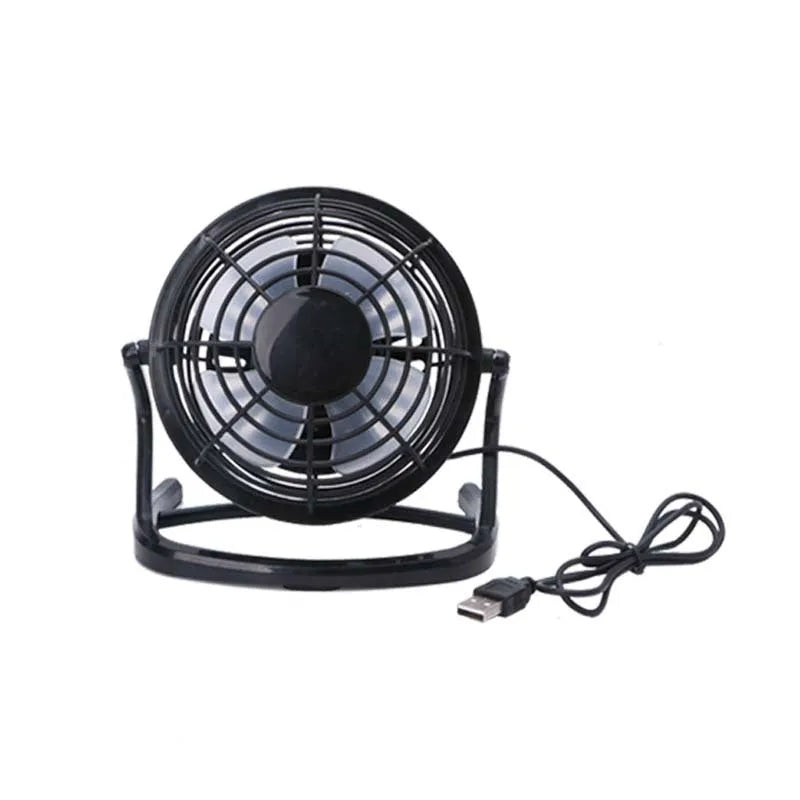 Mini black USB desk fan with adjustable head on a wooden desk next to a laptop.