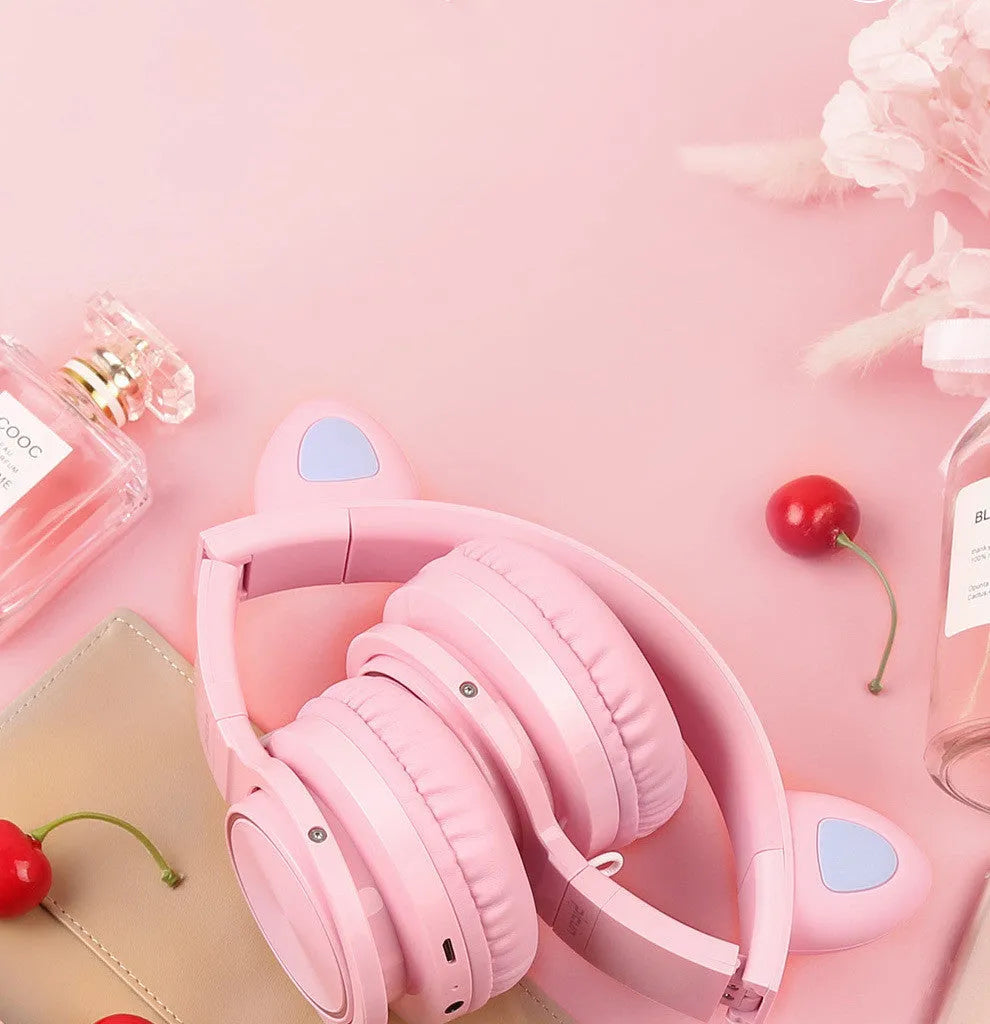 Pink and white Luminous Bluetooth wireless over-ear headset with microphone on a table.
