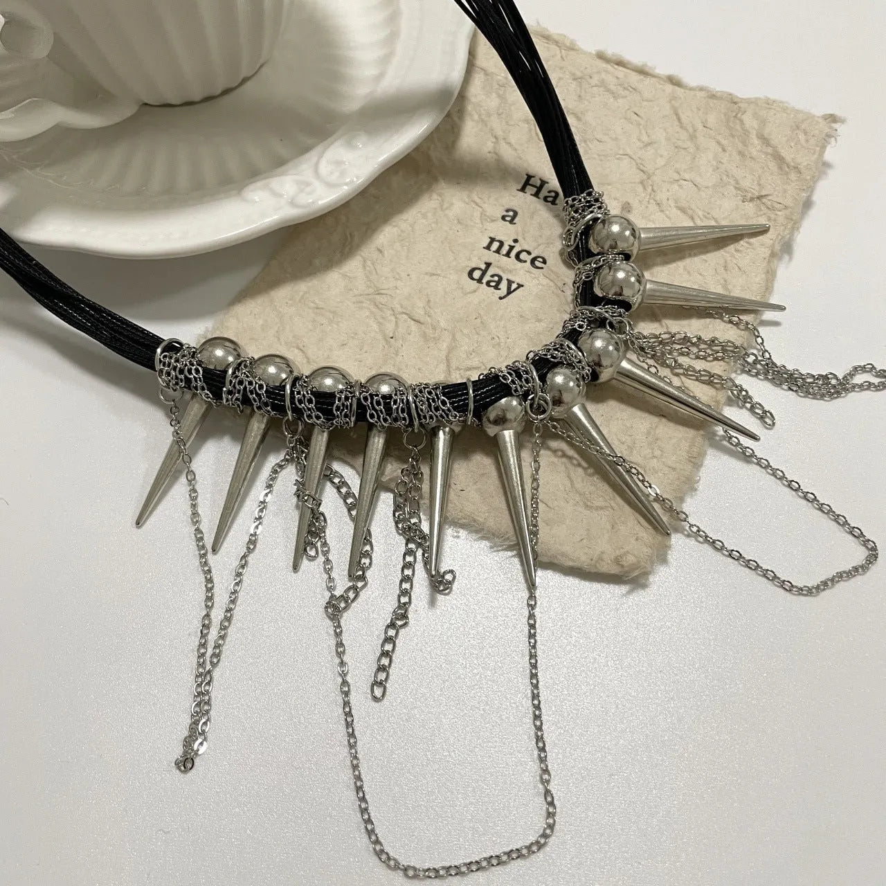 Women's leather necklace with round beads, a winding tassel, and silver point rivets on a casual outfit.