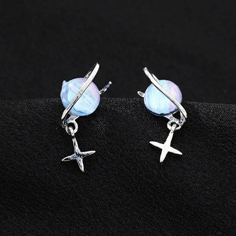 Metal geometric planet earrings in multicolour finish on a neutral background