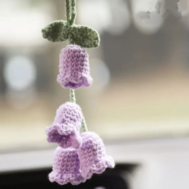 Green and white knitted wool car plant decoration with macramé texture and a white hanging rope.