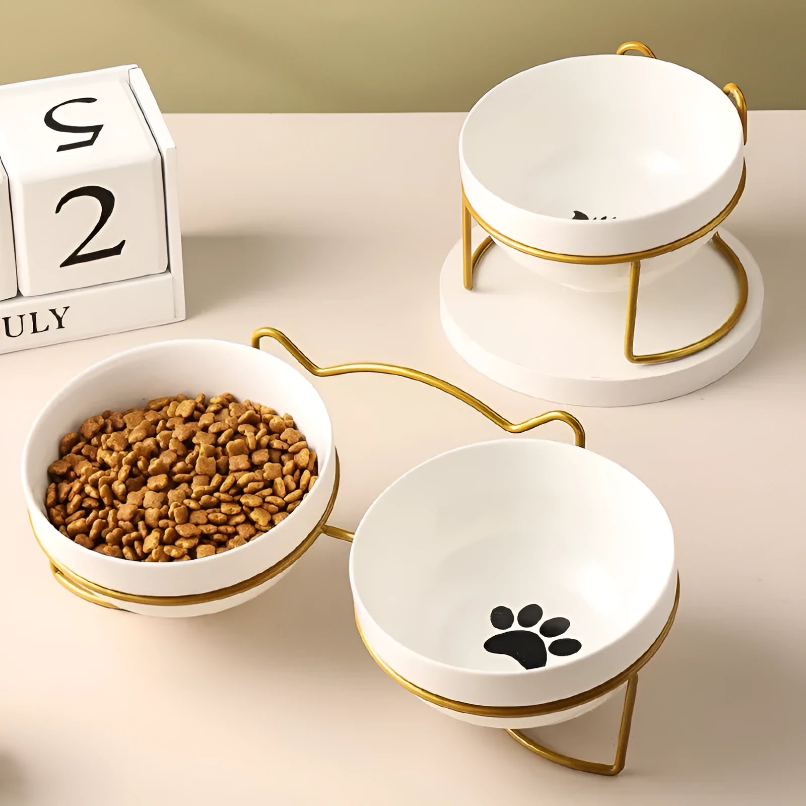 White ceramic cat bowl with cat paw print design on a black iron frame stand